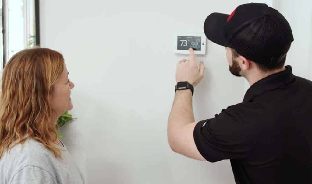 HVAC technician from Handy Bros. adjusting a smart thermostat, to ensure comfort in the customers home.